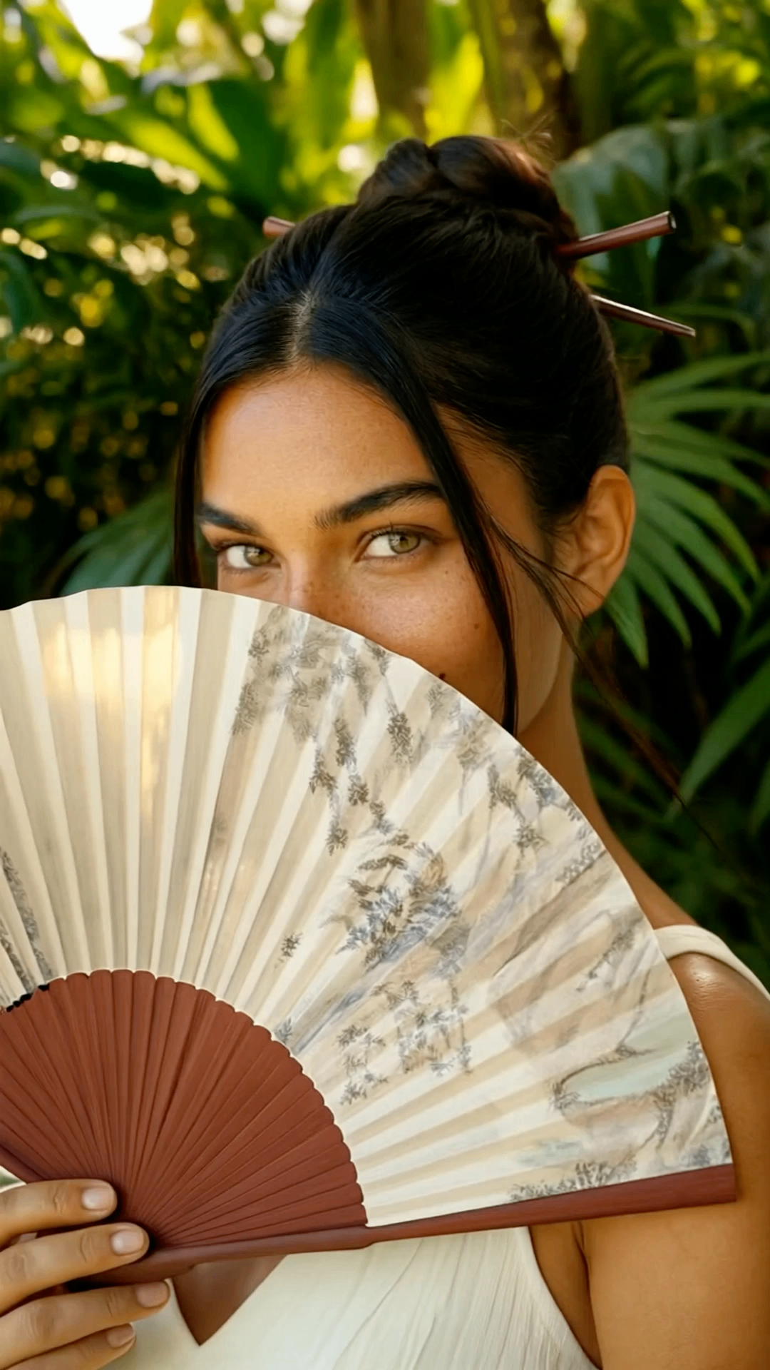 Portrait of a guest holding a folded fan in lush tropical surroundings