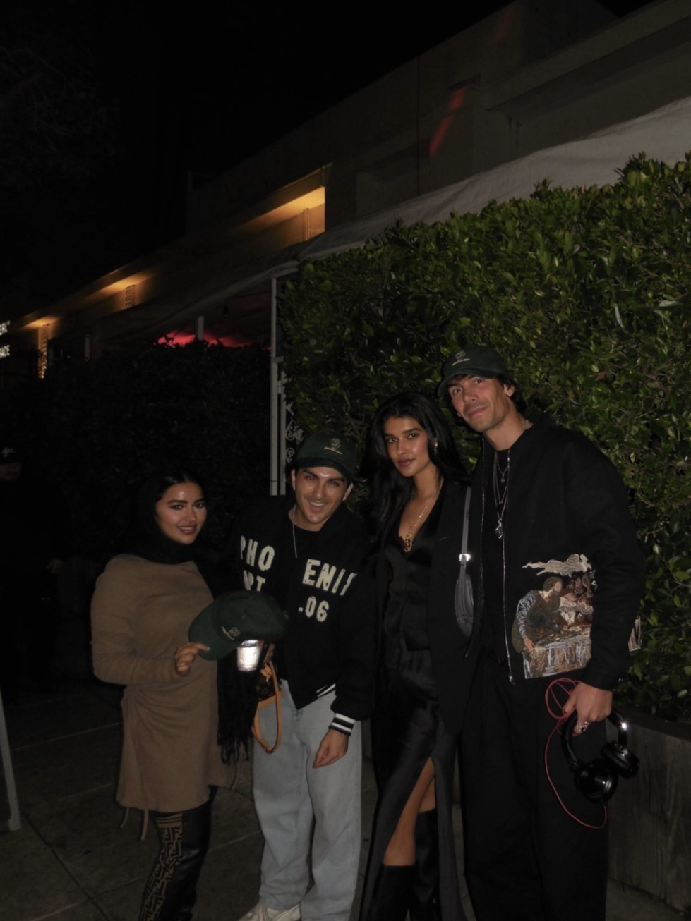 Group photo outside a venue at night, headphones in hand